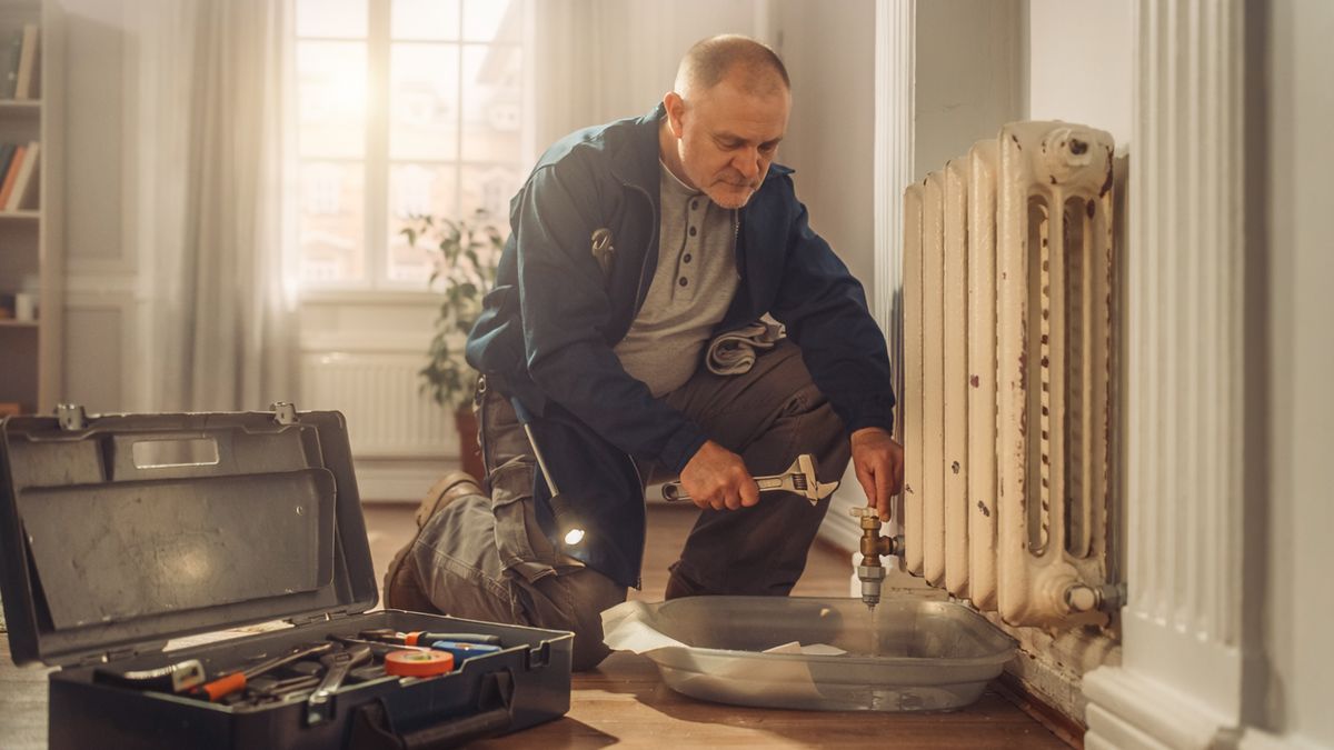 A building superintendent repairing a radiator