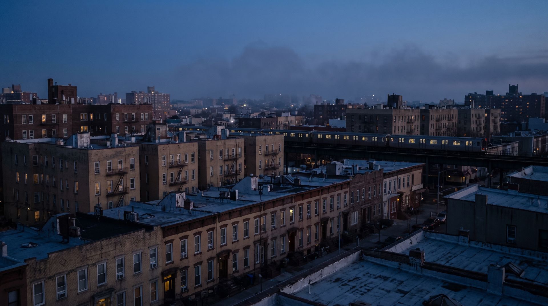 Queens rowhouses at blue hour with the elevated subway line crossing the middle distance